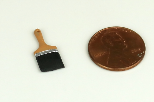 Miniature wide-bristle paintbrush next to a penny on a white background