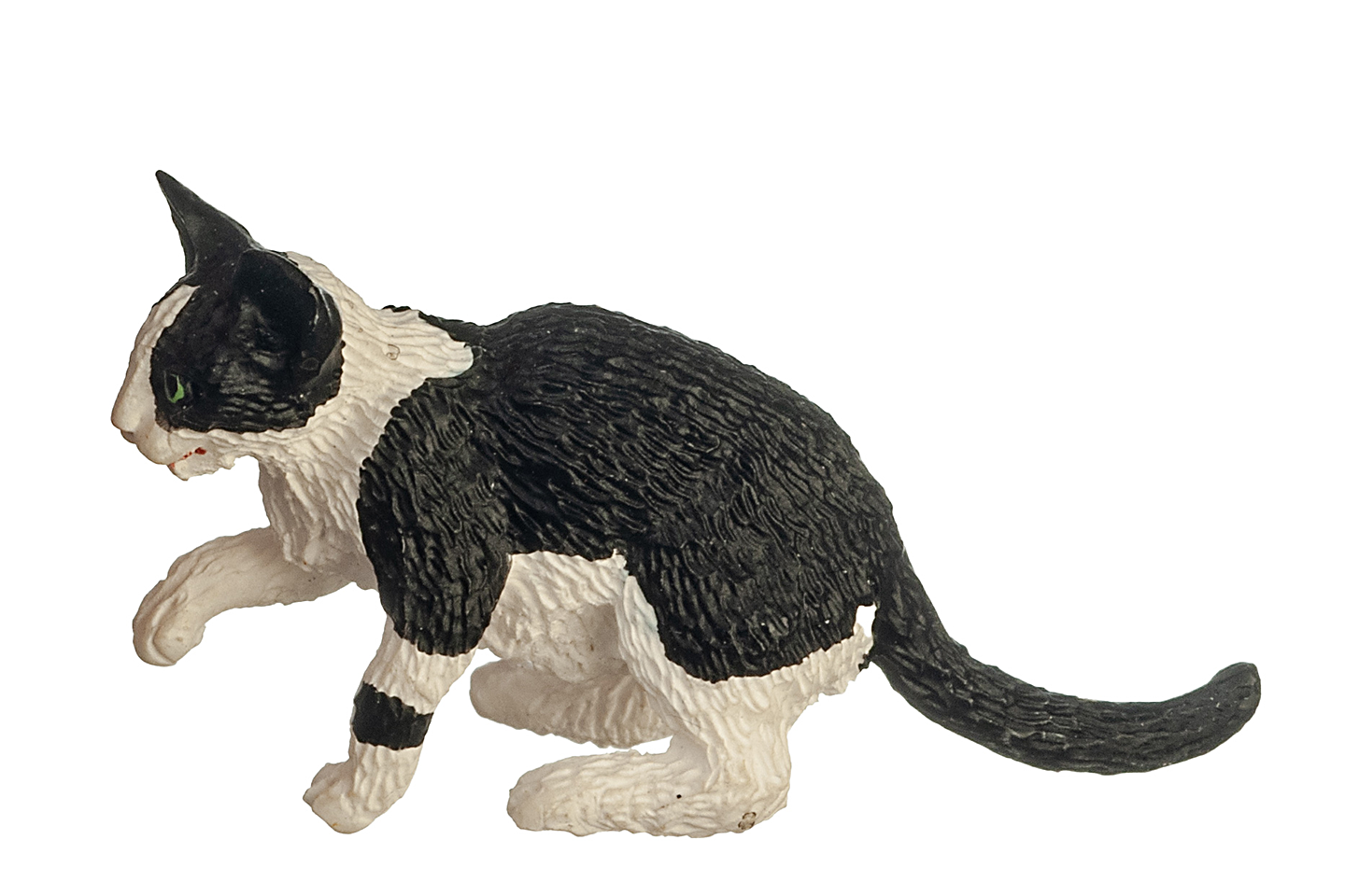 A side view of a black and white cat with green eyes, sitting with its right paw raised in a playful pose, on a white background. It has one black spot on its left paw and the rest of its paws and legs are white. Its back and tail are all black. It has a white stripe down its nose, having a typical "mask and mantle" coat pattern.