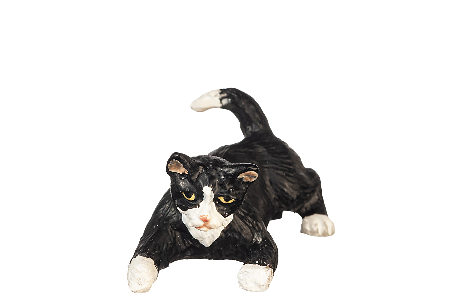 Black and white tuxedo cat with green eyes figurine, in a crouched playful position, on a white background