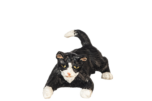 Black and white tuxedo cat with green eyes figurine, in a crouched playful position, on a white background