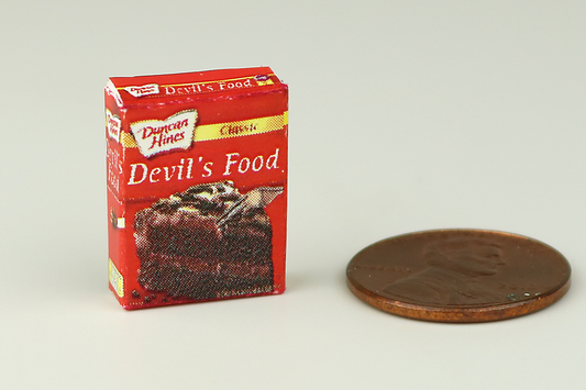 Miniature box of devil's food cake mix next to a penny on a white background