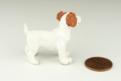 White Jack Russell Terrier miniature dog figurine with red ears next to a penny on a light gray background
