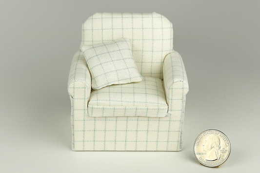 Miniature armchair in a pale robin's egg blue plaid print on a cream background, with a matching pillow, pictured on a gray background, next to a quarter for scale.